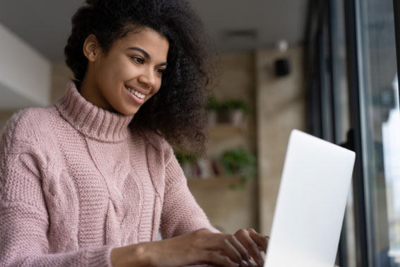 Smiling young woman working on a laptop.